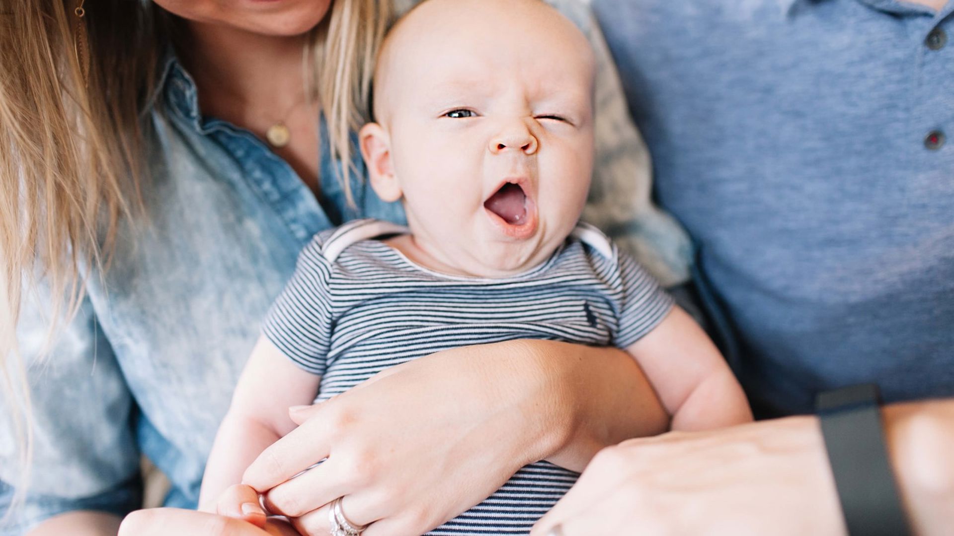 Baby yawning in his parents arms after being born using their GMHBA cover