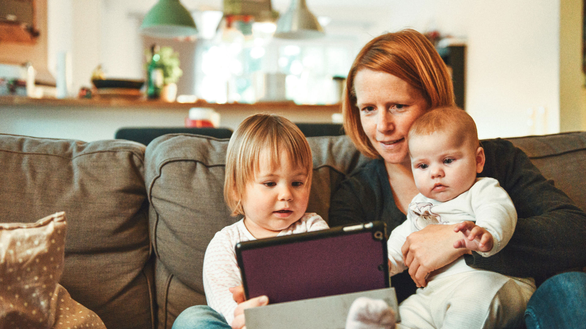 single mother with two children on the couch looking at laptop