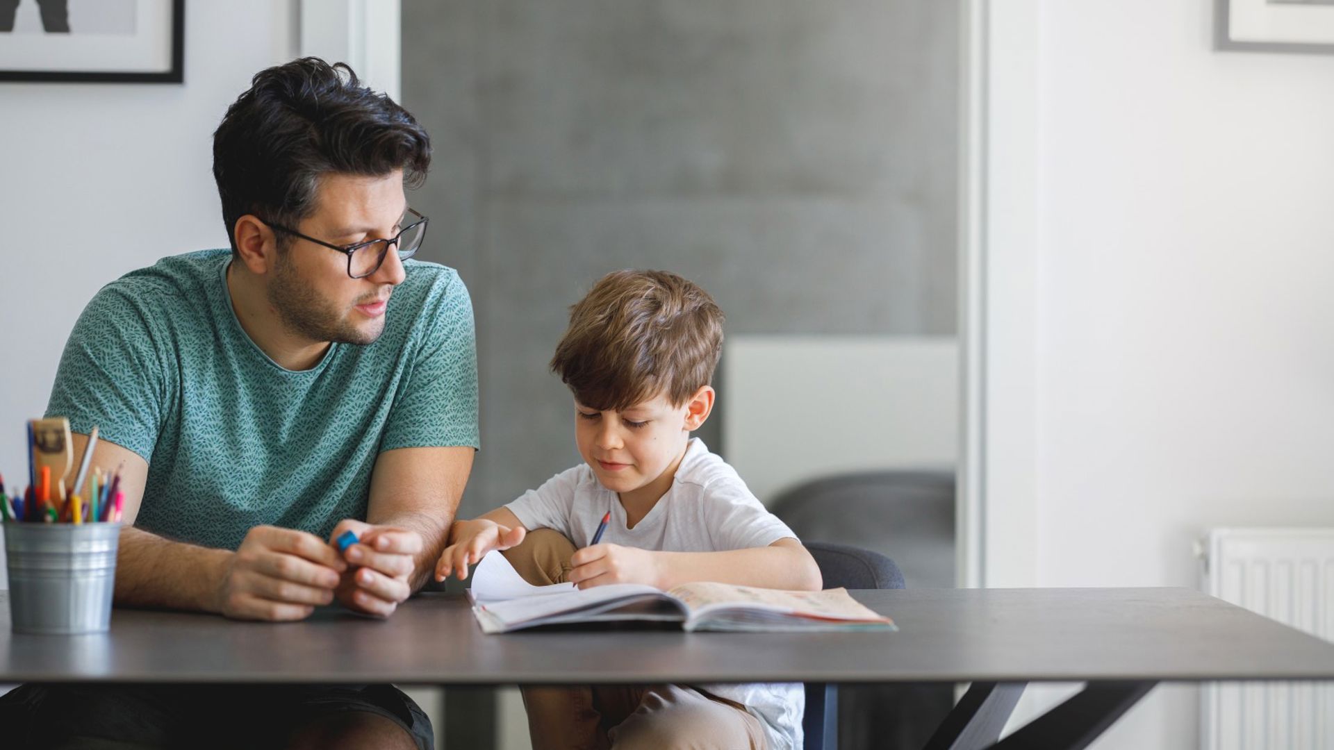 Young father with glasses doing homework with his son
