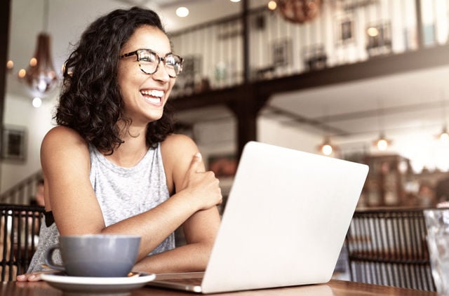 Woman wearing glasses in cafe with her laptop.