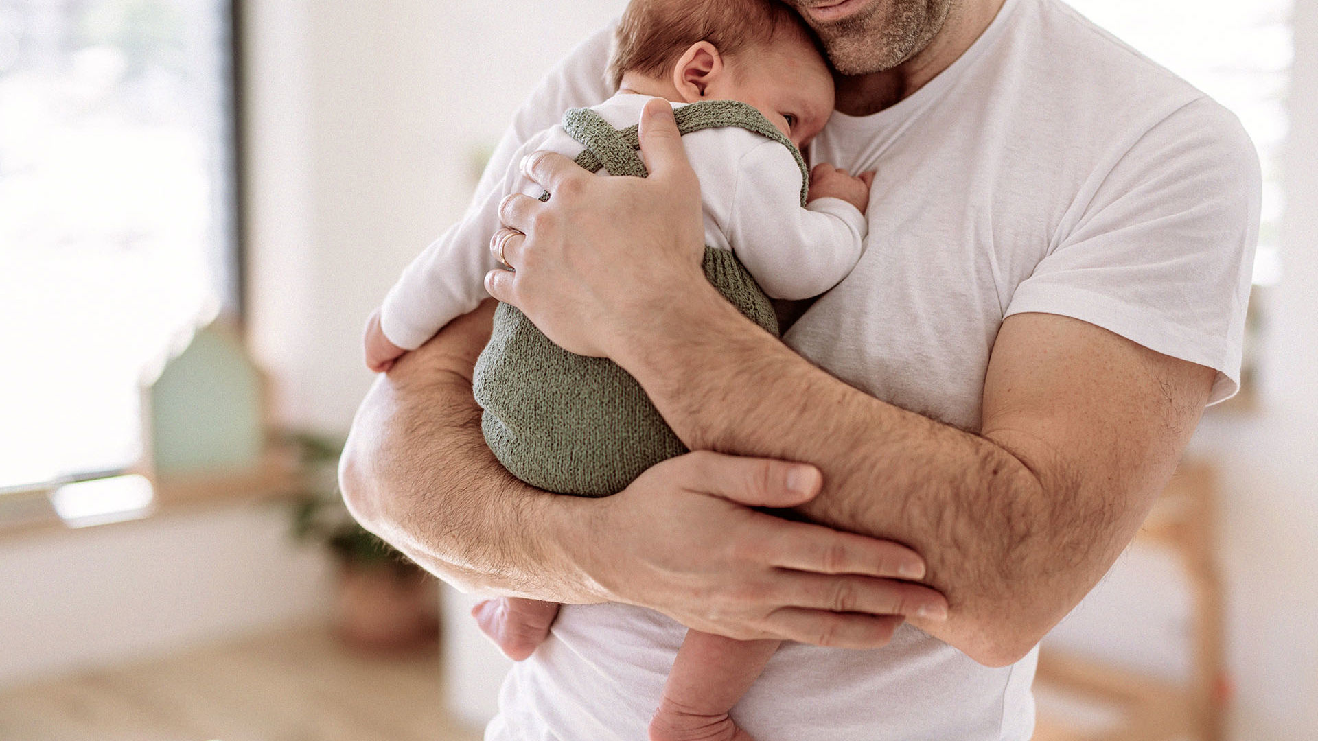 dad holding newborn baby to his chest for a hug