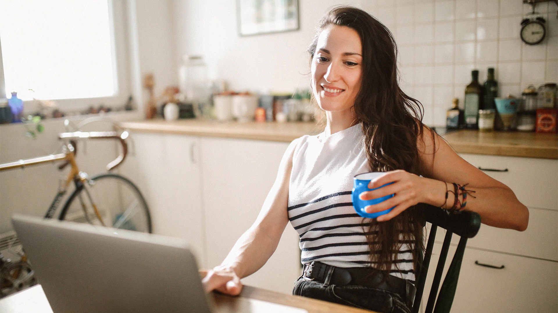 female enjoying a coffee in her kitchen researching health insurance