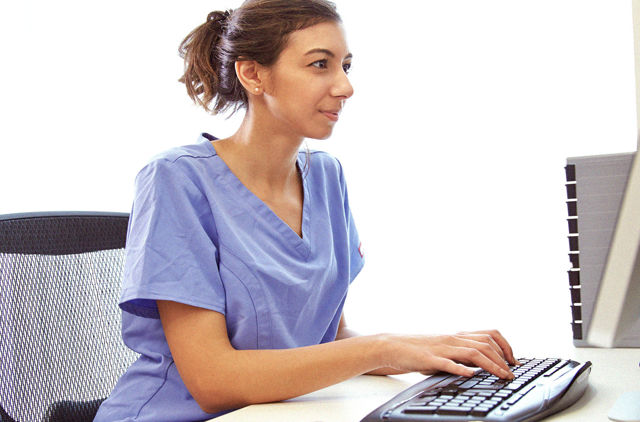 Nurse in scrubs using a computer