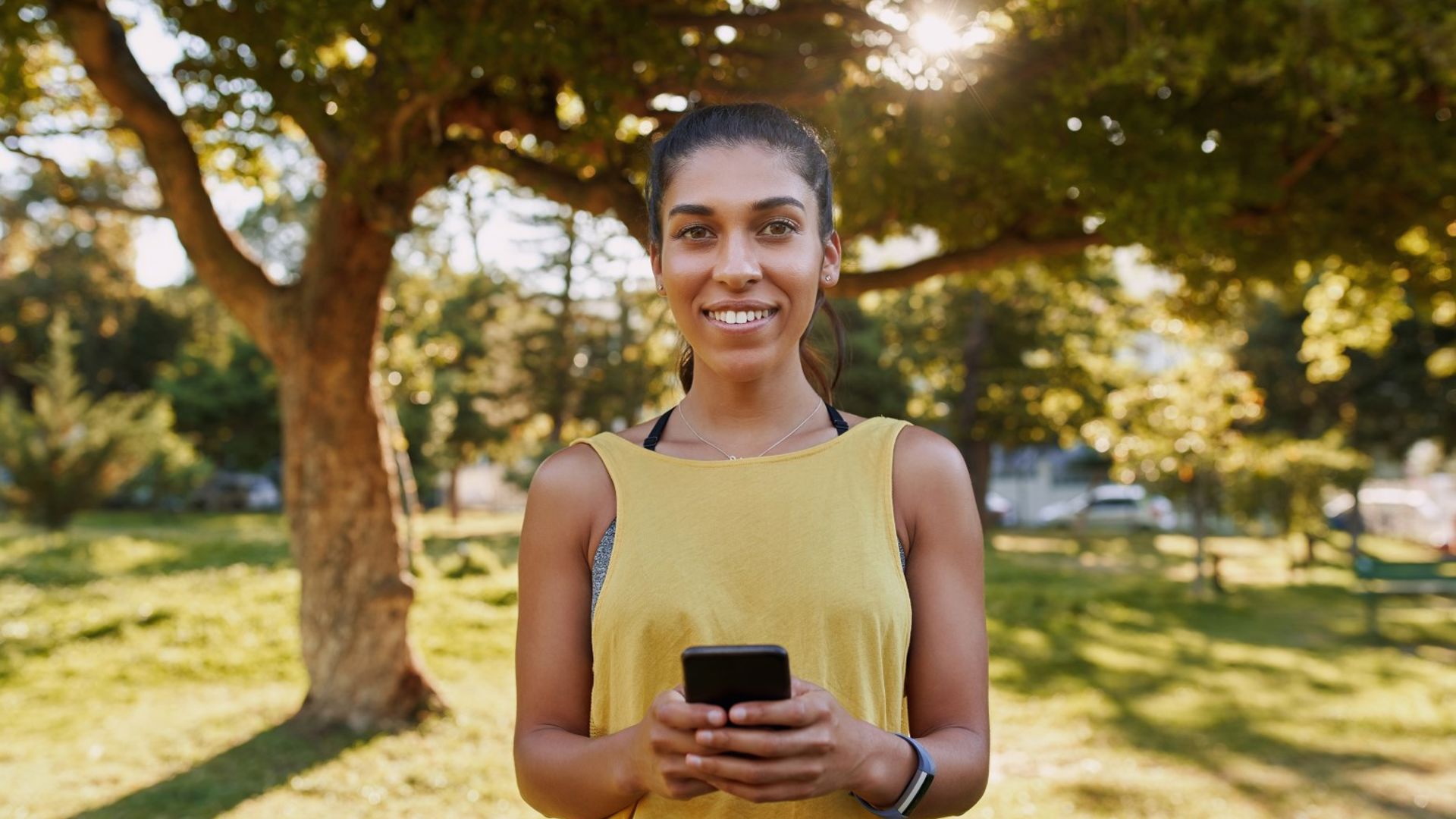 Young sporty woman holding mobile phone in a park