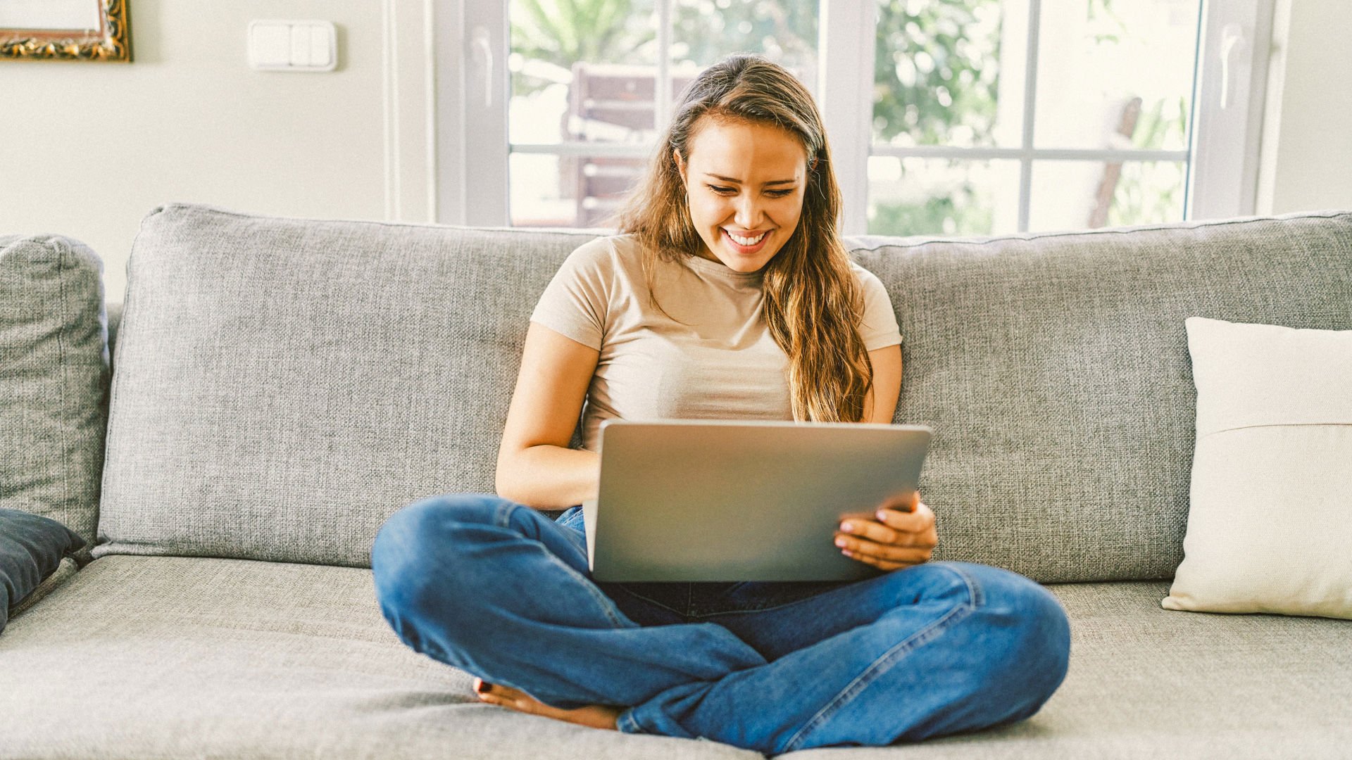 Young woman sitting on couch joining GMHBA on her laptop